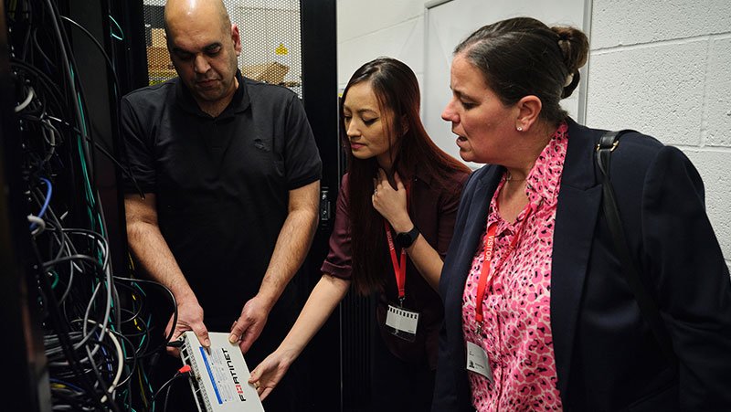Jisc and Aston Manor staff look at a Fortinet device.