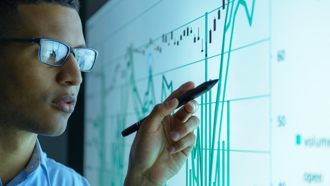 Businessman studying graphs on an interactive screen in business meeting, close up.