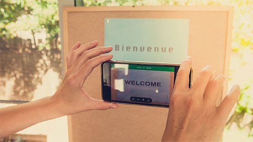 A mobile phone translation app translates "bienvenue" to "welcome".