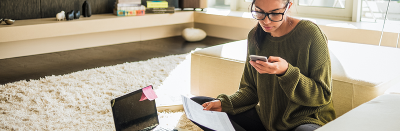 A female student checking her phone and laptop at home.