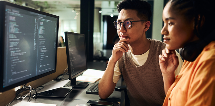 Computer programmers working on code at night in office: teamwork and problem solving - stock photo