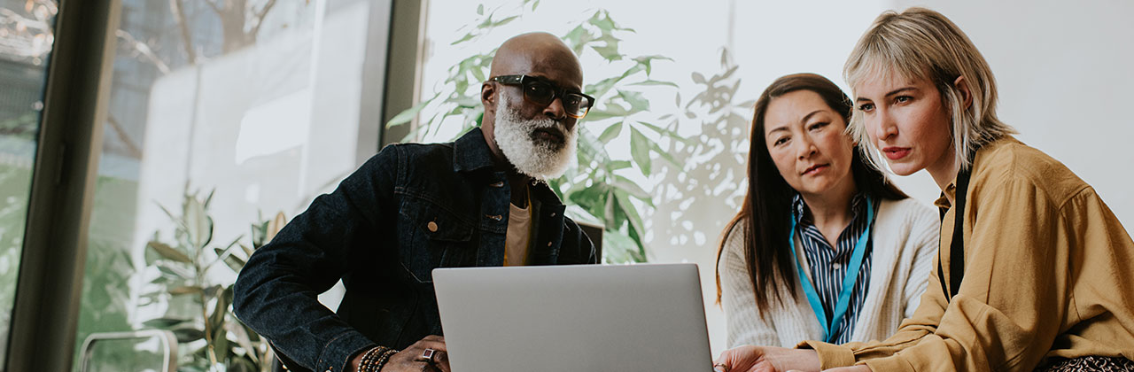 A consultant discusses digital transformation with work colleagues at a computer.