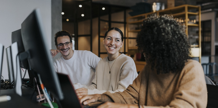 Female computer programmer discussing strategy with happy colleagues