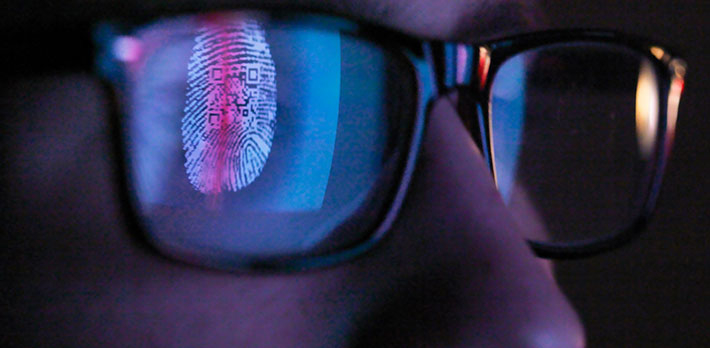 A finger print scan is reflected in someone's glasses.