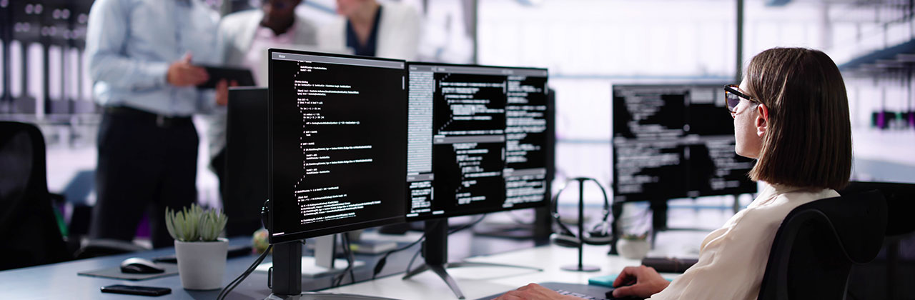 Woman looking at code on screens.