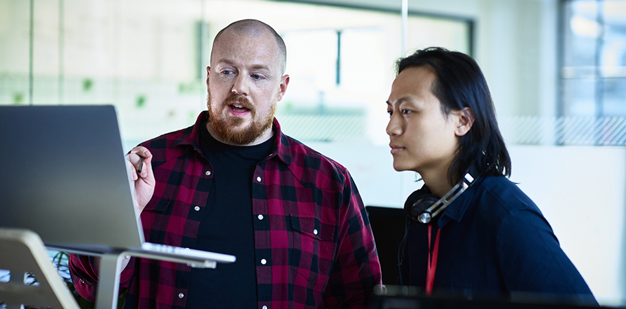 Two male college workers looking at a computer screen.