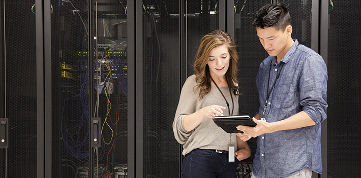 People examine data in front of a server.