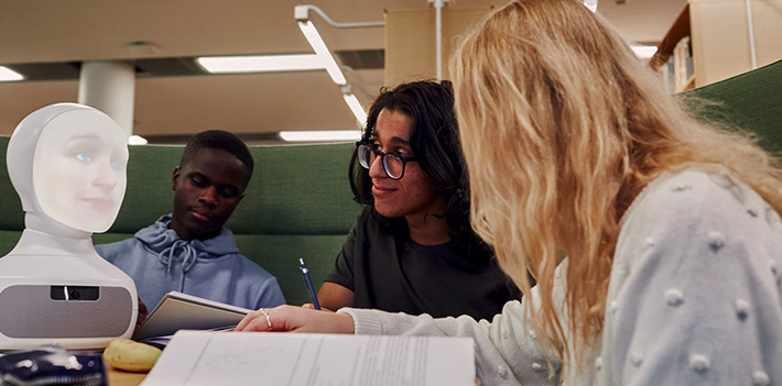 Students study together in a library with a robot.