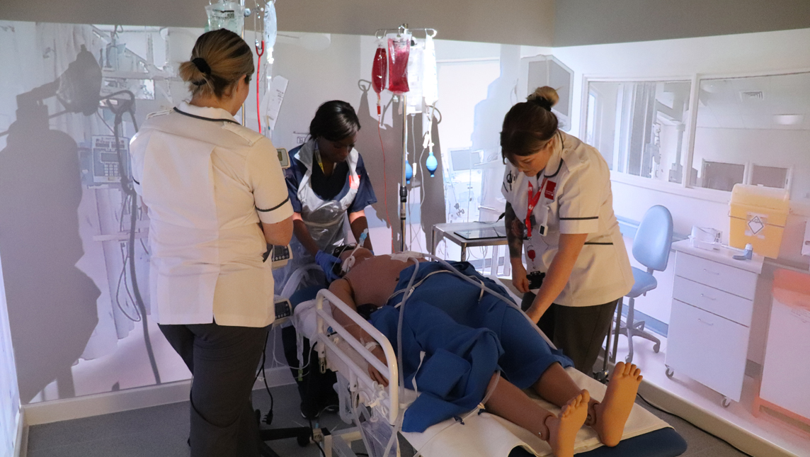 Two students using an immersive room to simulate a hospital