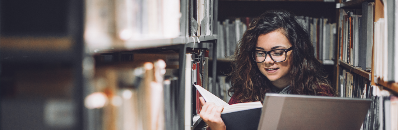 A woman with a laptop in a library.