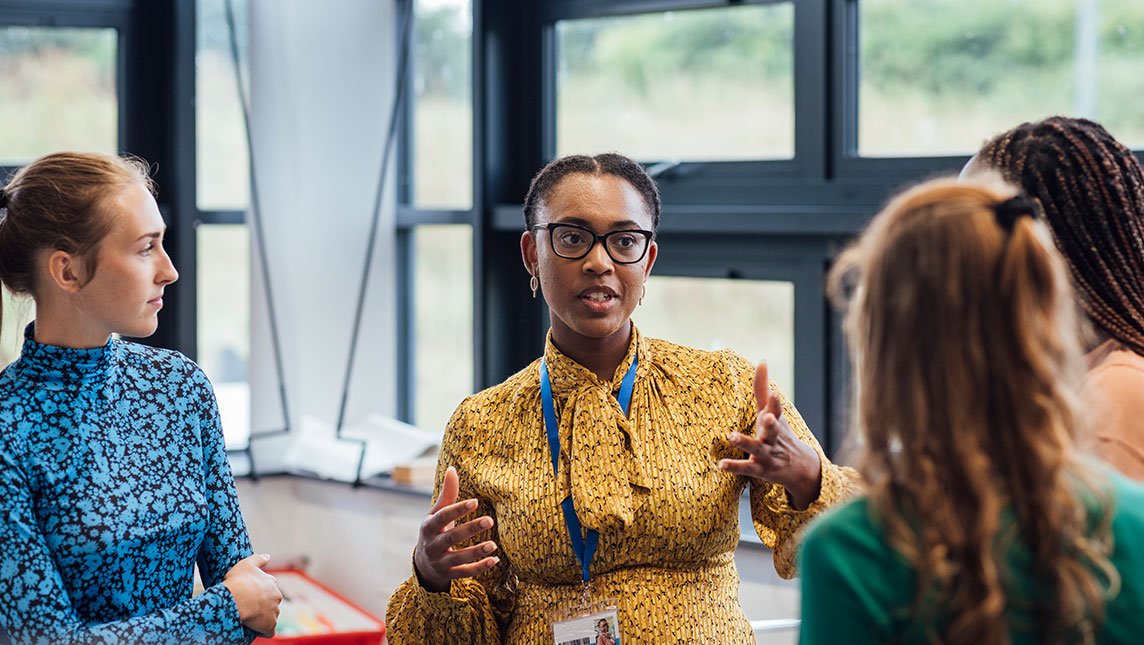 A teacher discusses feedback with a group of students.