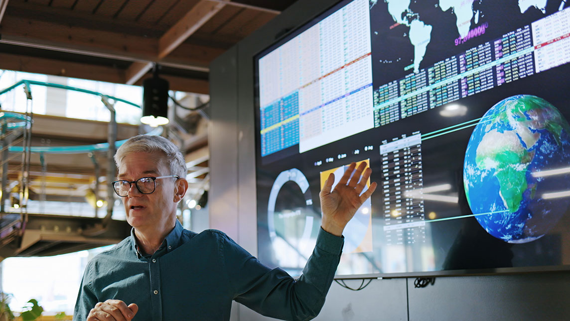 A man presents data on a digital screen.