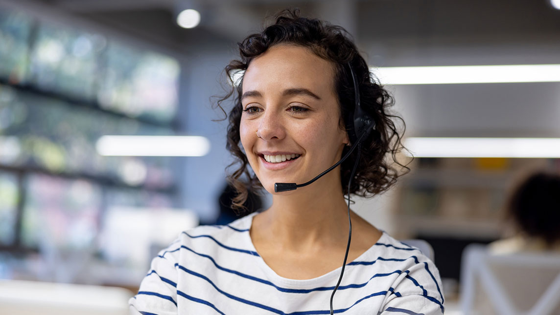 A worker using a headset talks with her colleagues.